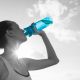 woman drinking from a blue water bottle outside