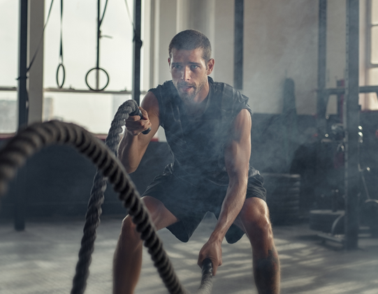 man swinging ropes at gym