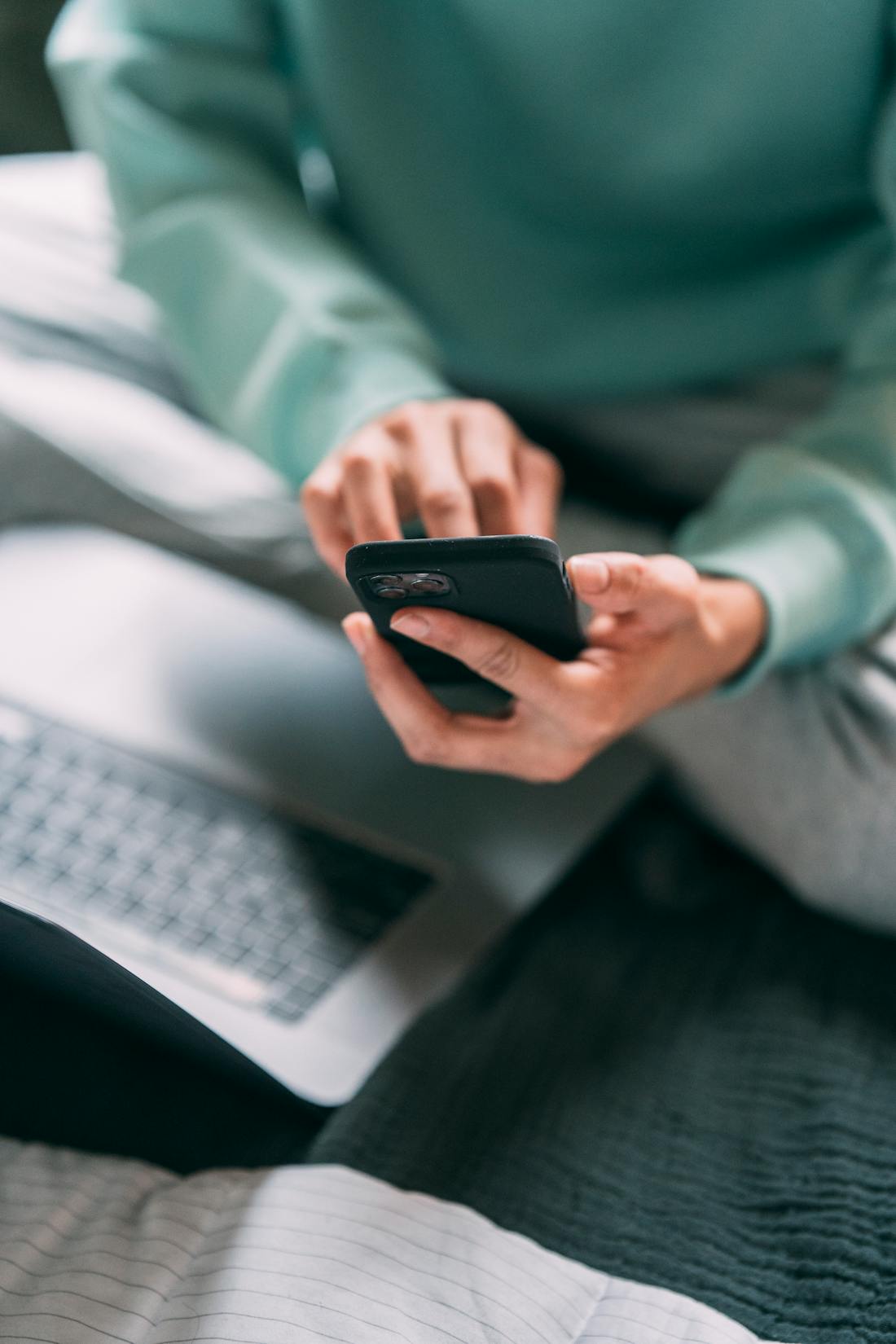 Person using smartphone and laptop for active tech brain training exercises to boost focus and prevent digital dementia