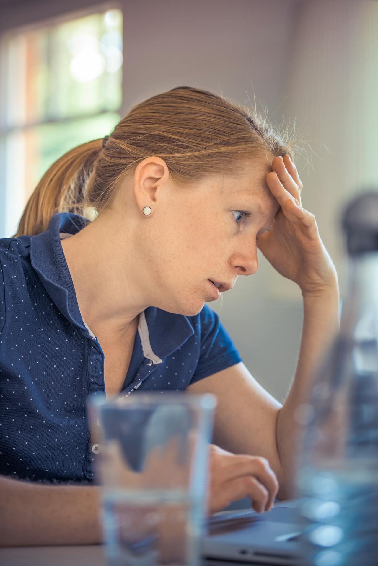 Tired woman at a desk rubbing her forehead, struggling to focus in the afternoon, illustrating creatine for brain fog and a simple daily plan to help.